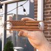 Hand holding a wooden personalized bottle opener engraved with an American flag design, perfect for unique gifts or personal use.