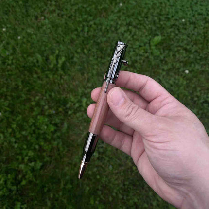 Our Cedarwood Bolt Action Ballpoint Pen, held by one of our Maker's against a grassy backdrop