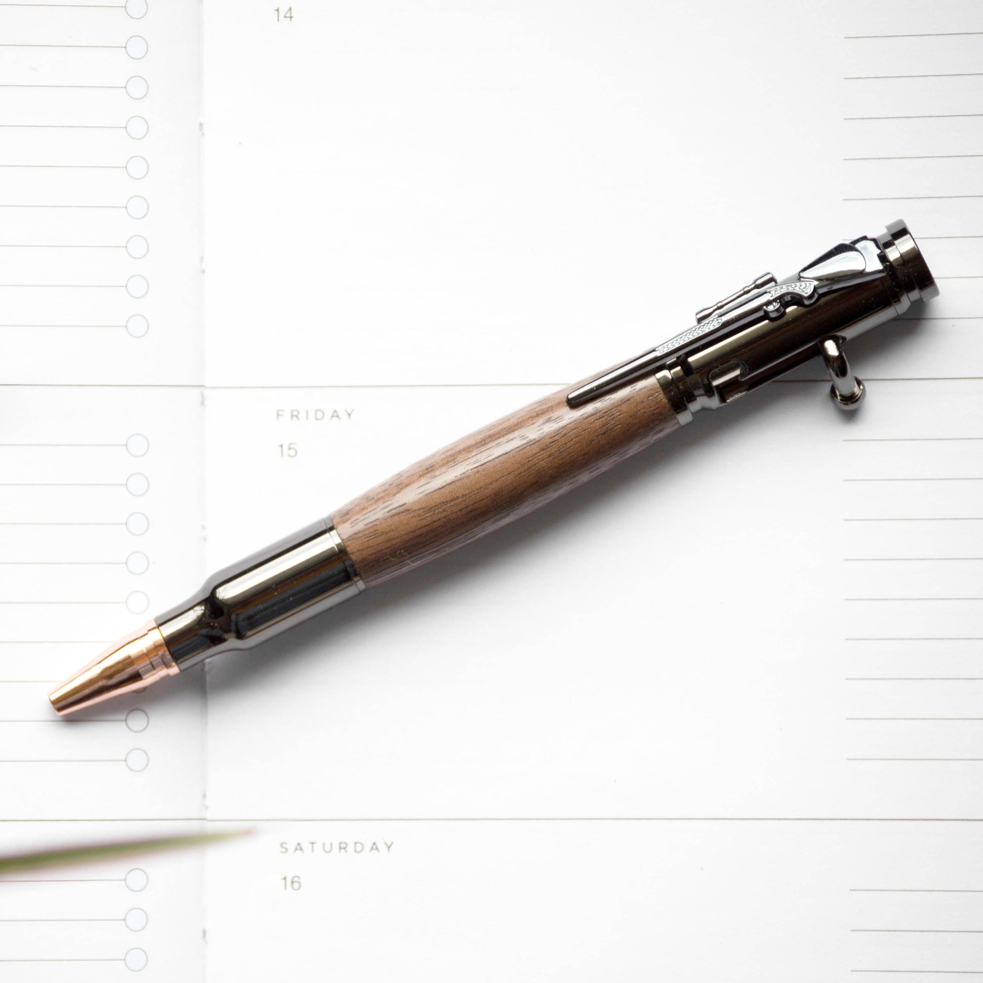 Black Walnut Bolt Action Pen by Autumn Woods, photographed against a white planner page